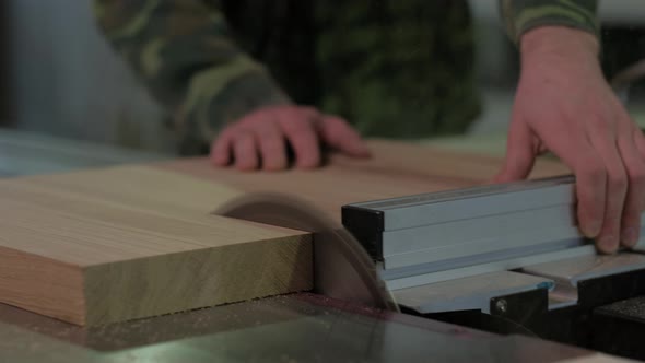 Worker in Camouflage Sawing Wood on The Machine