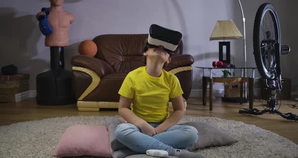 Close-up of Caucasian Male Teen Sitting in VR Headset, Looking Up, Smiling and Talking. Charming Boy