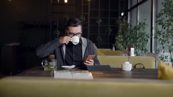 Man Using Smartphone at Table in Cafe