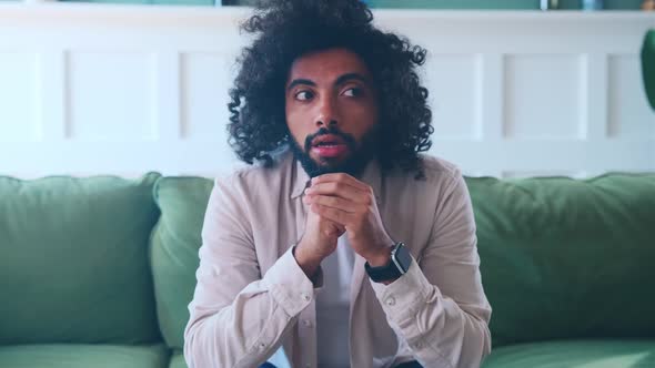 Young Perplexed Arabian Man Nervous Thinking About Problems Sits on Sofa