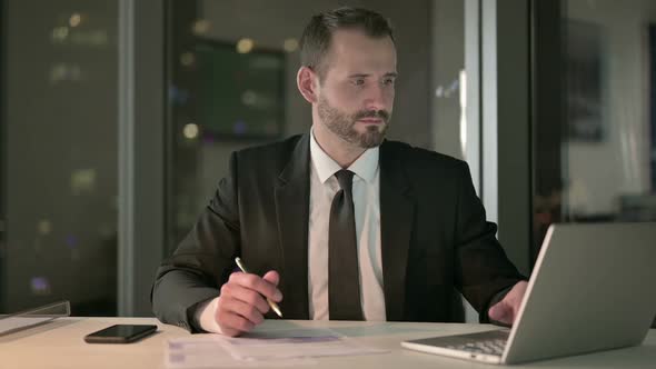 Smart Businessman Working on Laptop and Document at Night