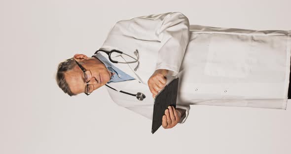 A Mature Doctor Professional Dressed in White Apron Shirt with Glasses and a Stethoscope Around