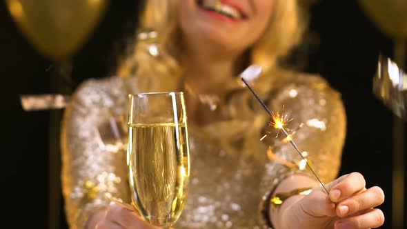 Smiling Woman Showing Glass of Champagne and Bengal Light to Camera, Party