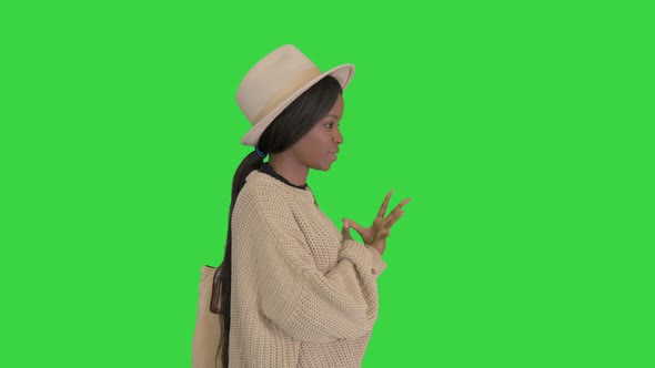 Young African American Woman in Knitwear and White Hat Talking and Gesturing on a Green Screen