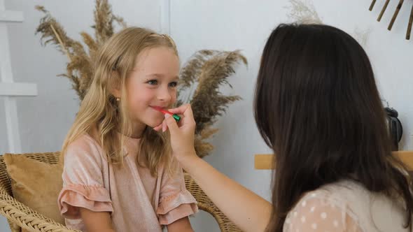 Mother Painting Lips of Little Daughter at Home