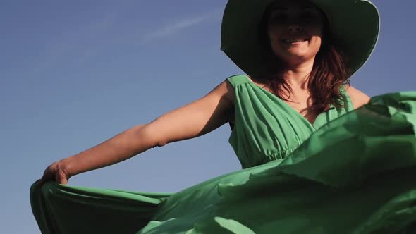 Young Woman in a Green Dress Posing on the Background of a Beautiful Landscape