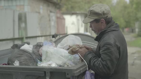 A Beggar Homeless Man Tramp Is Looking for Food in a Trash Can. Kyiv. Ukraine