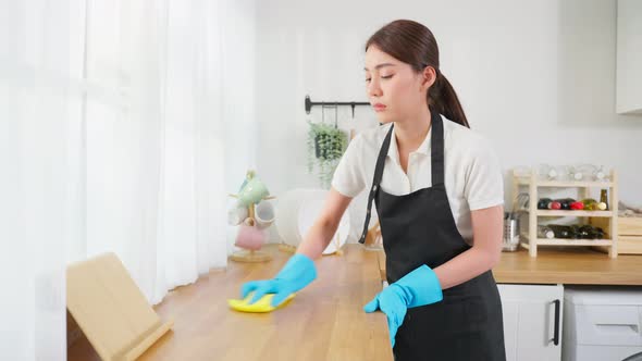 Asian woman cleaner feeling frustrated while wiping messy dirty cooking counter for housekeeping.