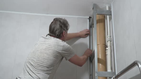 A Man Tries on a Plastic Corner When Installing PVC Panels in Bathroom