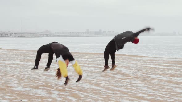 Male and Female Parkour Athletes Doing Tricks Together Outdoors in Winter