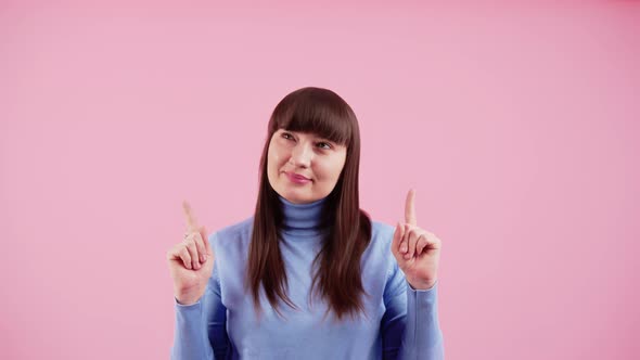 Positive Caucasian Brunette with Bangs Wearing Baby Blue Turtleneck Pointing Up with Two Index