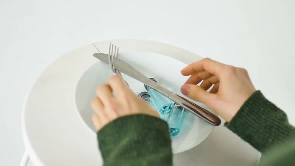 Woman is Going to Eat From White Plate with Glass Ampoules with Blue Liquid Inside Vaccination