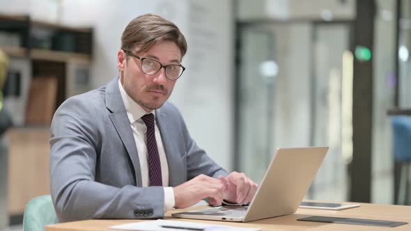 Serious Businessman with Laptop Saying No with Finger Sign