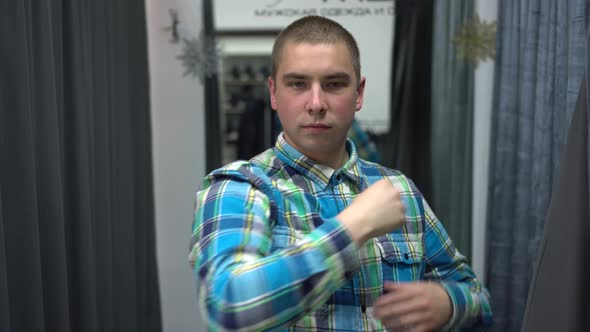 A Young Man Opens the Curtain in the Fitting Room. Clothing Store.