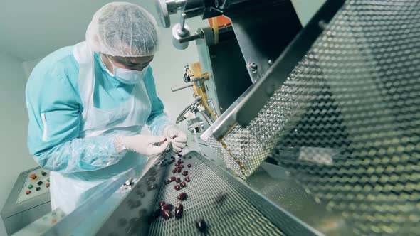 Conveyor Belt Transporting Pills Under Control of a Chemical Worker