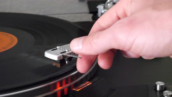 A record player needle raising slowly off of the spinning vinyl and the music stops.