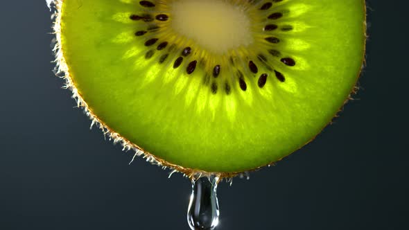 Super Slow Motion Macro Shot of Water Drop Falling From Kiwi Slice on Grey Background at 1000Fps