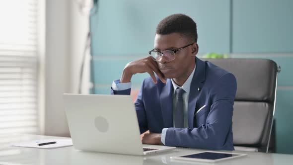 Young African Businessman Thinking While Working on Laptop in Office