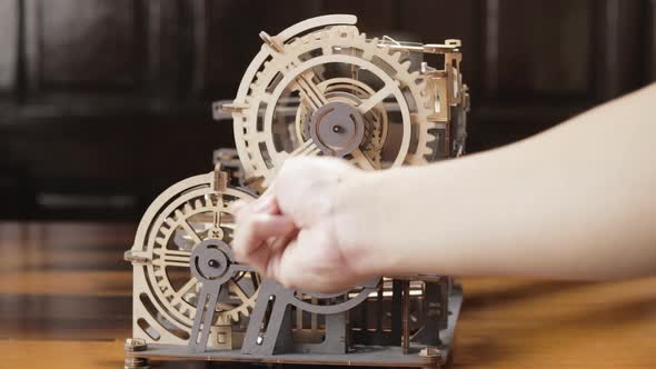 Hand Moving Wooden Gears Of A Toy Machine With Hand Crank. full shot