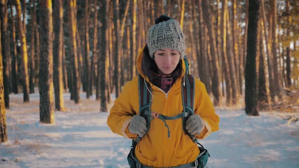 Young Travel Backpacker Woman with Backpack Walking in Snowy Winter Pine Forest