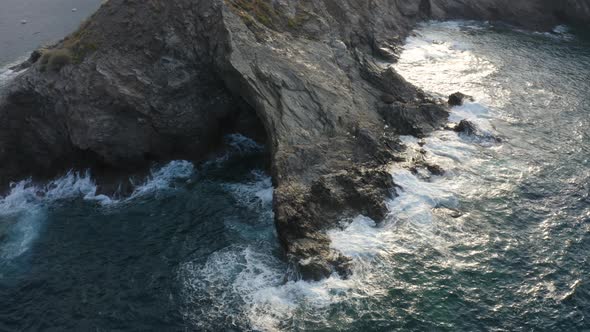 Aerial drone view of Sea waves crashing into rocky cliff. Flying above water 