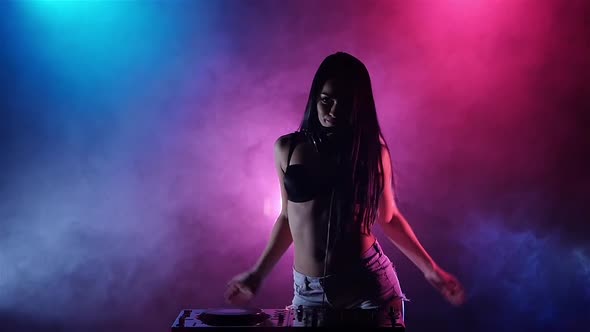 Girl DJ Dancing Develop Her Hair Behind Her Multicolored Lights and Smoke. Slow Motion