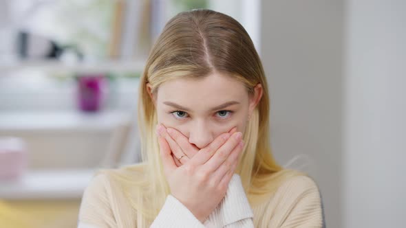 Portrait of Scared Young Slim Woman Closing Mouth with Hands Looking at Camera