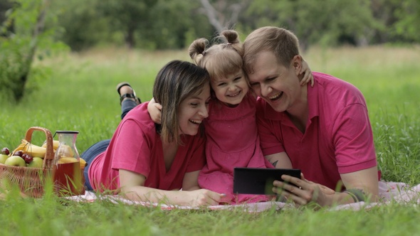 Family Weekend Picnic. Daughter Child Girl with Mother and Father Celebrate Success Online Shopping