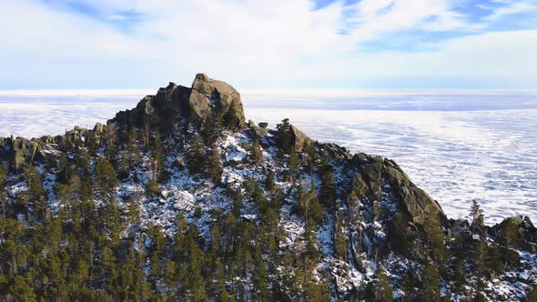 Flying over a snow-covered cliff on the shore of huge lake. Cinematic landscape