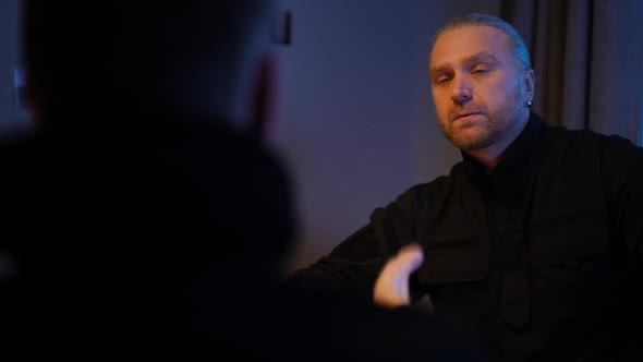 Portrait of Caucasian Policeman Smoking Listening to Witness Gesturing Talking Sitting at Table