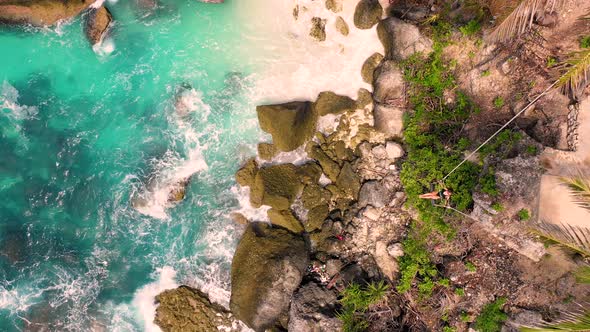 Aerial view of attractive woman swinging at Diamond Beach shore, Indonesia.