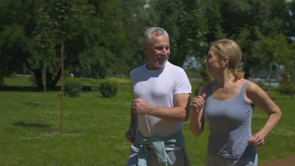 Mature Emotional Couple Jogging in Park, Active and Full of Energy, Slow-Mo
