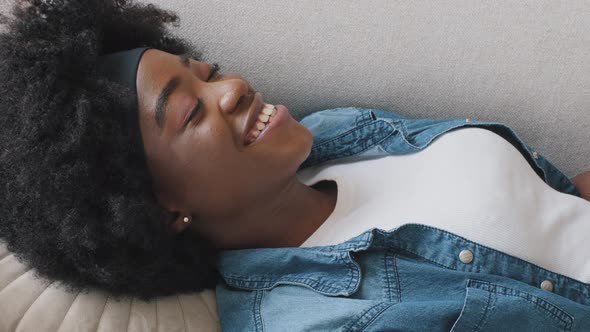 Smiling Serene Relaxed Young Adult Girl Rest Lying on Comfortable Sofa Calm Happy African American