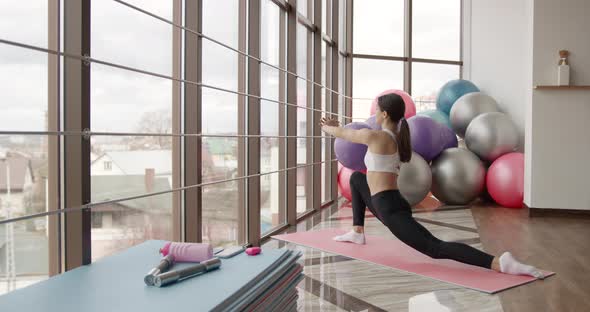 Athletic Woman Stretching on a Mat in a Fitness Studio