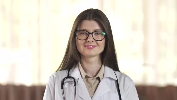 Portrait of a Smiling Young Female Doctor in Stylish Glasses Satisfied with Her Work in the Hospital