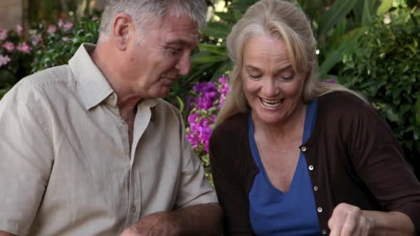 Happy mature couple, woman feeding cake to husband