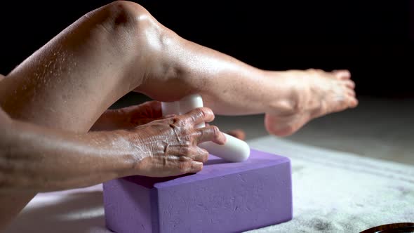 Low extreme closeup view of mature woman using a massage tool for stretching calf muscles.