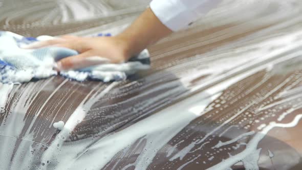 Mans hand washing surface of expensive car with sponge, business driver, job