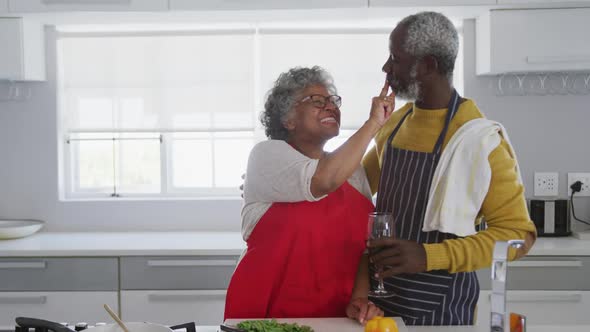 An african american couple spending time together in the kitchen social distancing in quarantine.