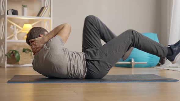 Side View Wide Shot of Strong Middle Aged Man Pumping Press Lying on Exercise Mat