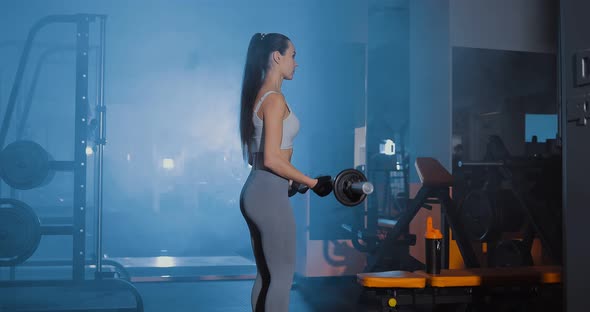 Girl Lifts the Barbell in the Gym