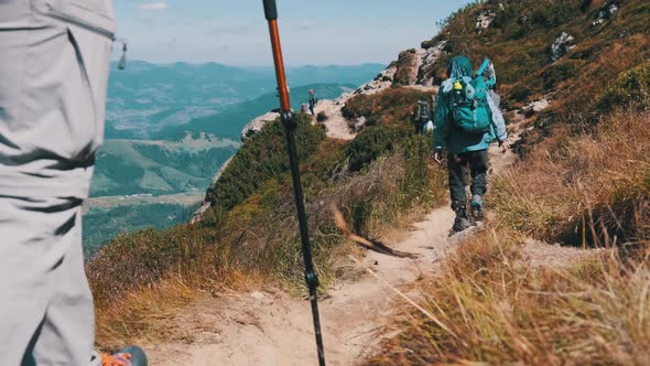 Group of Tourists and Children with Backpacks Go Down on Stone Trail in Mountain