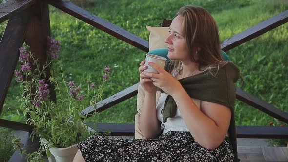 Charming Girl Sitting in Armchair Drinking Tea Outdoor