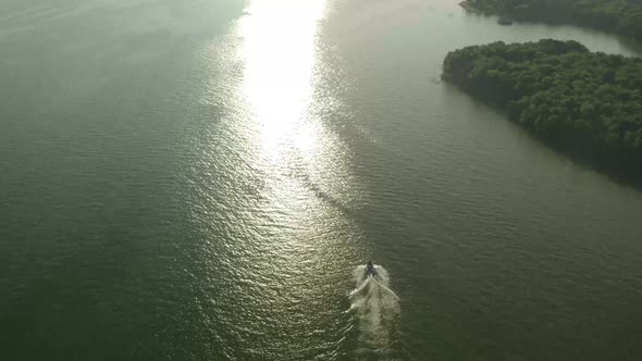 A motorboat all alone in the open waters heading towards a shoreline.