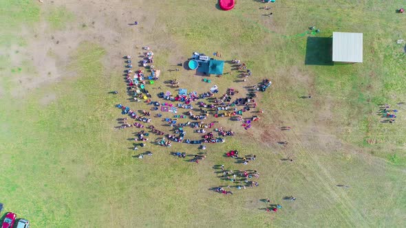 Descending top down shot of crowd with people getting baptized in a field.