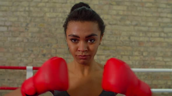 Portrait of Determined Athletic Black Female Fighter Clasping Boxing Gloves