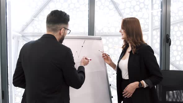 Woman Showing Statistics on Whiteboard to Coworker