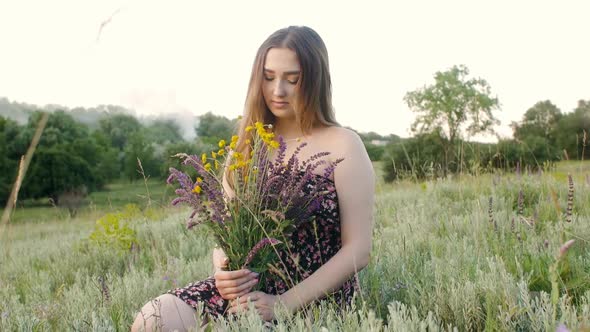 beautiful girl with bouquet of wildflowers on meadow, young woman with long hair in dress 