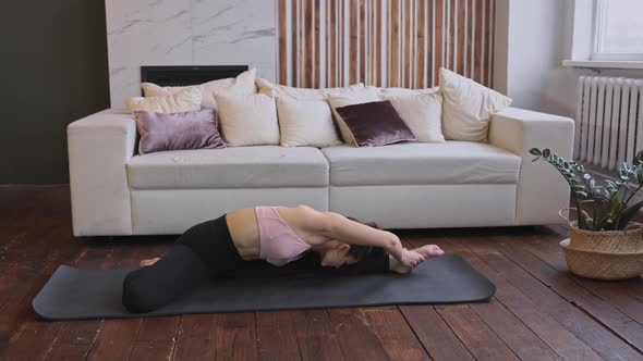 Young fit sporty brunette woman wearing sportsweartop do exercises on mat in living room