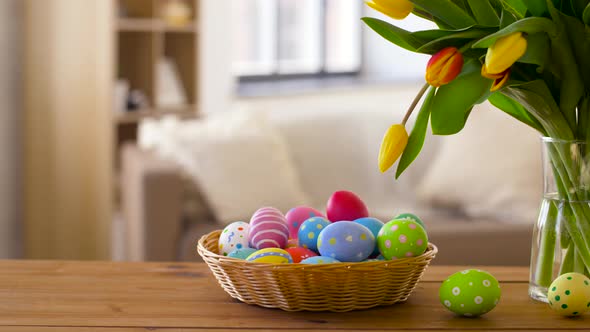 Colored Easter Eggs in Basket and Flowers at Home